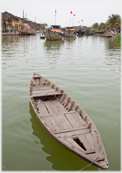 Rowing boat with larger boats beyond.