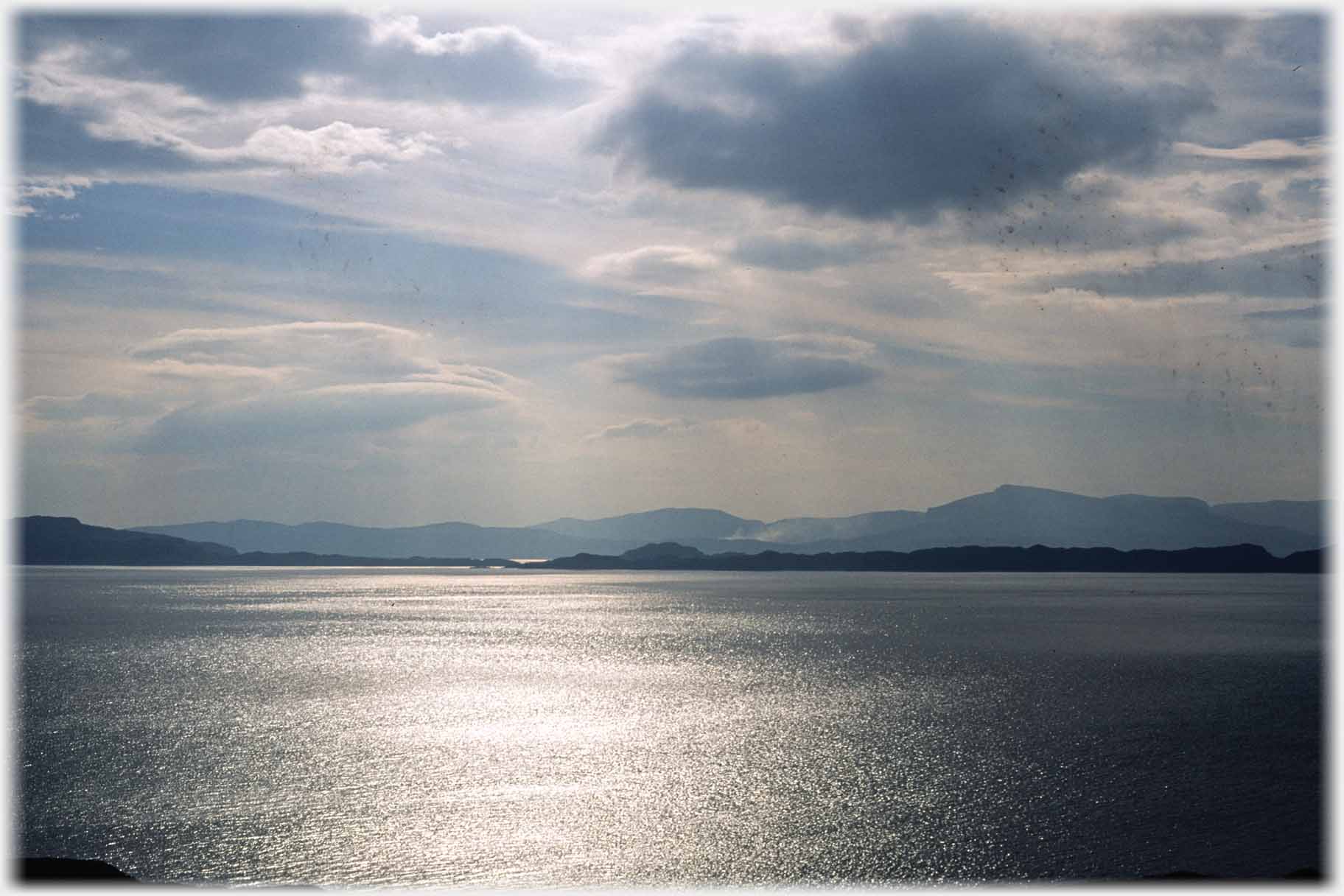 Light glinting on the sea with hills beyond.