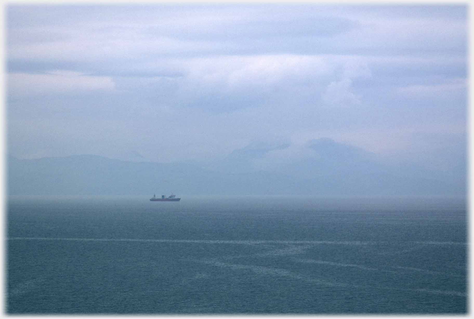 Ship in middle distance and mist covered hills beyond.