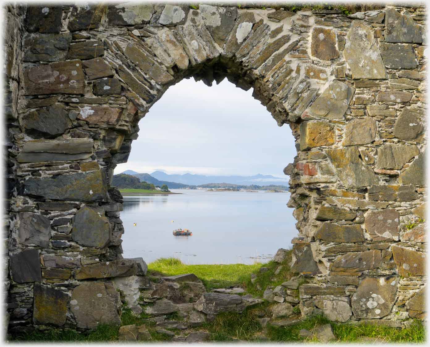Looking through stone window frame out to sea with Skye on horizon.