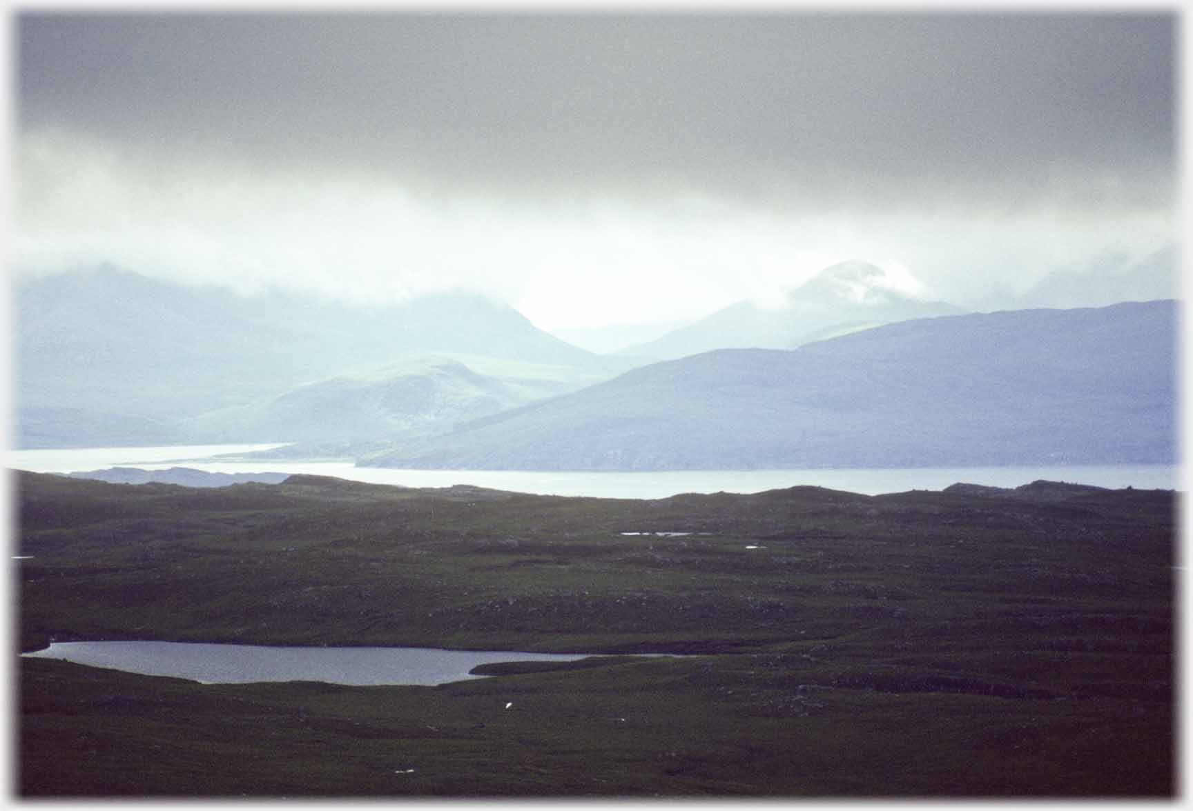 Gloomy foreground with heavy clouds, sea and hills.