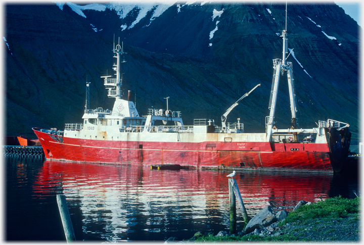 Red fishing boat against black hillsides.