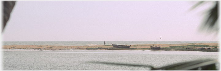 Spit of sand with figure and two boats.