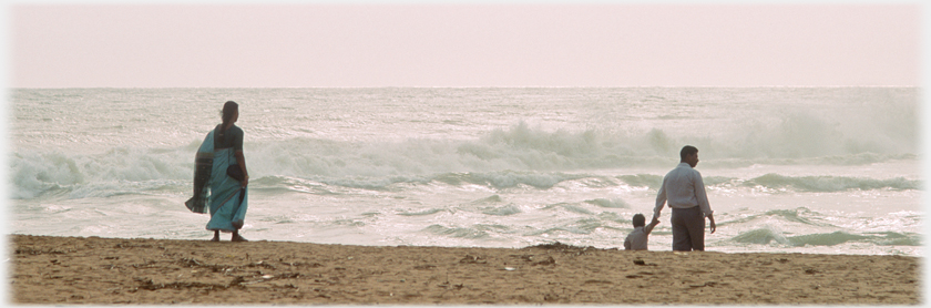 Woman, man and child looking out at waves.