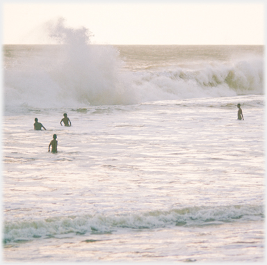 Four bathers face and large incoming wave.