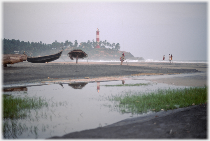 Figures on the beach near the lighthouse.