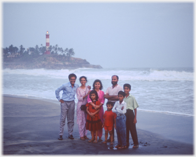 A family poses with the lighthouse behind.