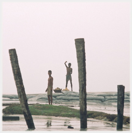 Two men one waving from on sandbags.