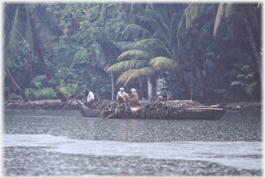 Punt with punter palm leaves and two men sitting.