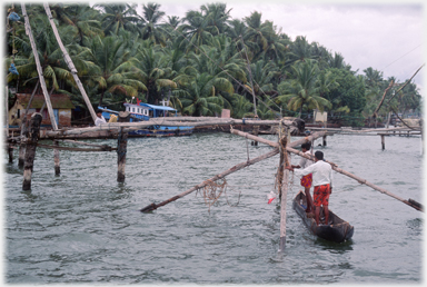 Two men in canoe working on net frame.