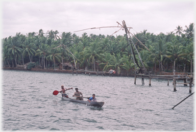 Three men passing nets in a canoe.