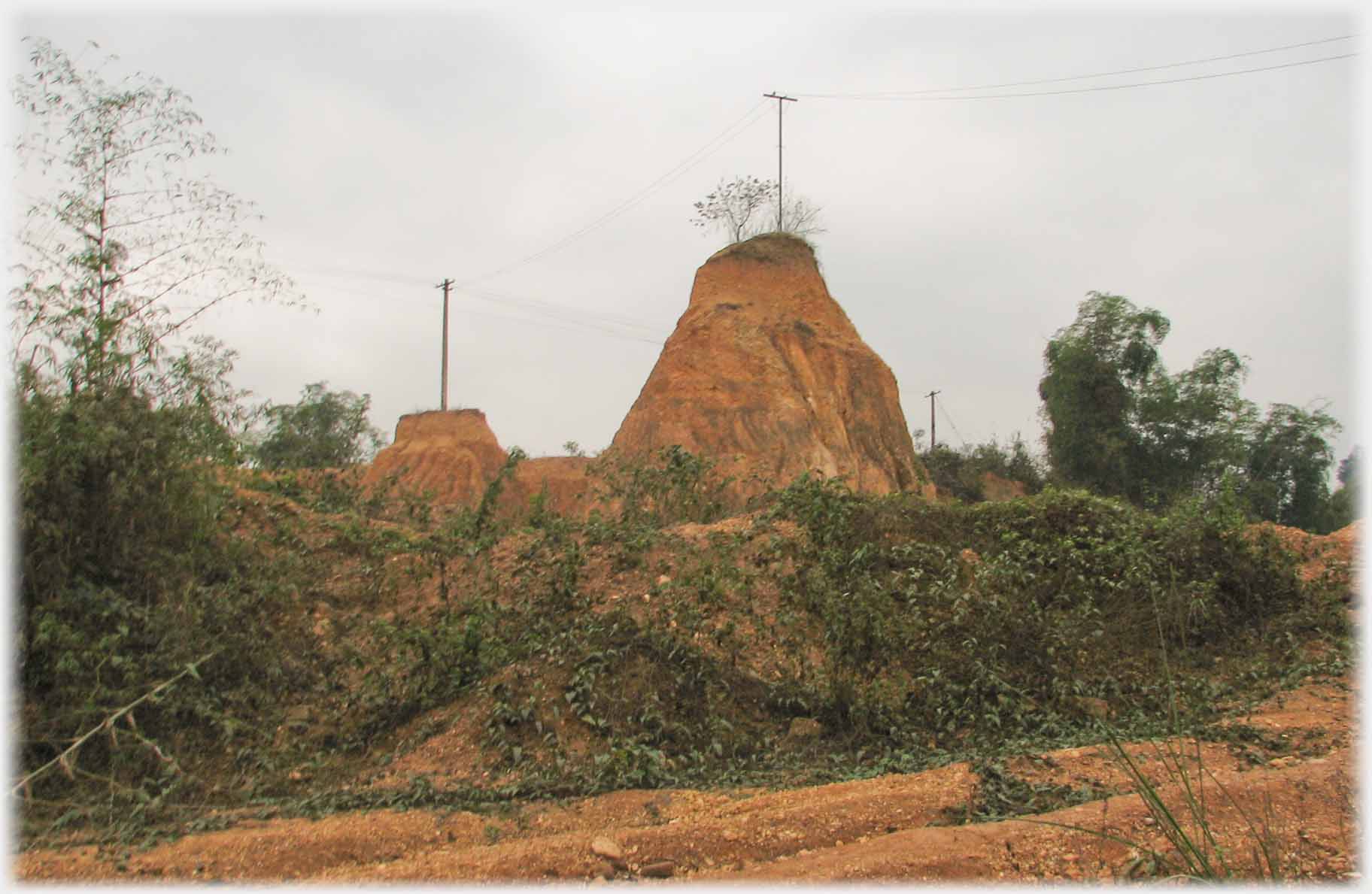 Two high mounds of earth with electricity poles on top.
