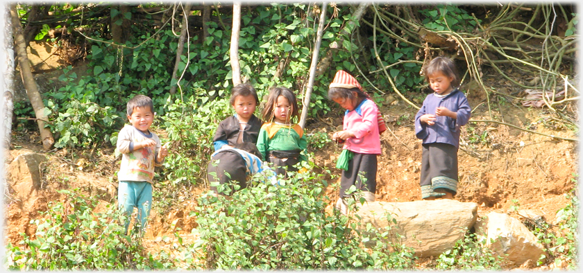 Five early school age children variously looking at the photographer while holding various objects.