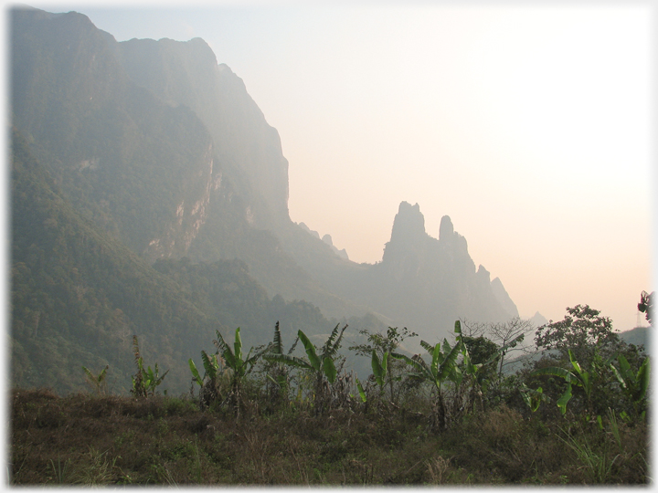Jagged outcrop beside high karst hills, bananas in foreground.