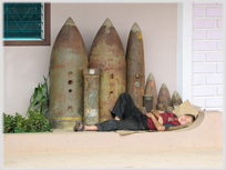 Figure sleeping beside bombs.