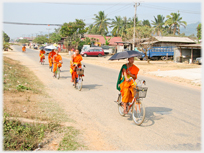 Monks riding bikes with umbrellas.