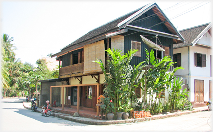 Substantial wooden corner house with large satellite dish.