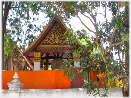 Small building covering large gong with robes hanging in front.