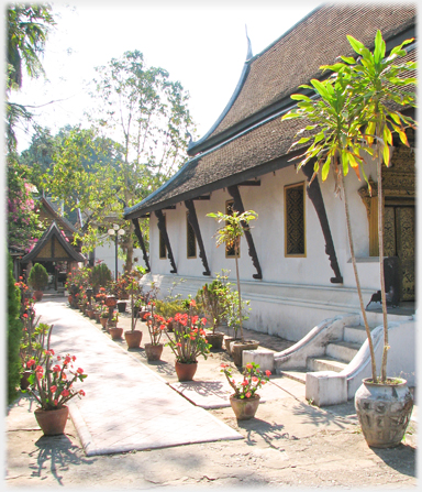 White wall with windows and simple roof supports.