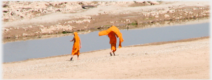Two monks walking by inlet.