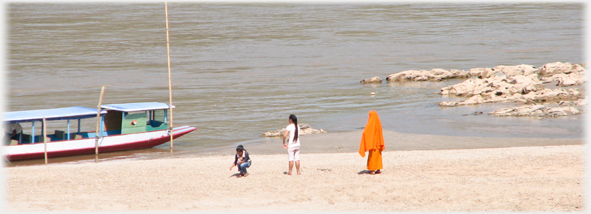 Monk two girls and boat at a river.