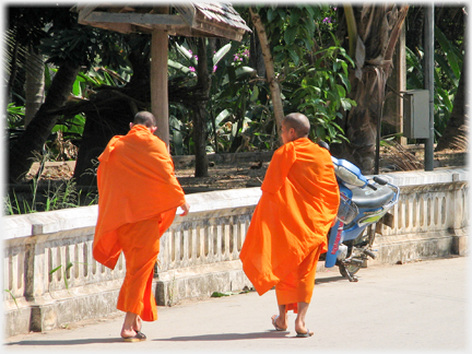 Two monks walking on a street.