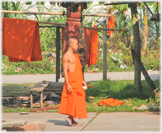 Monk standing holding mug, robes airing behind him.