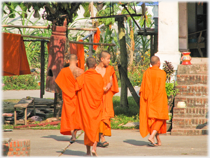 Group of three monks with one turning towards a passing monk.