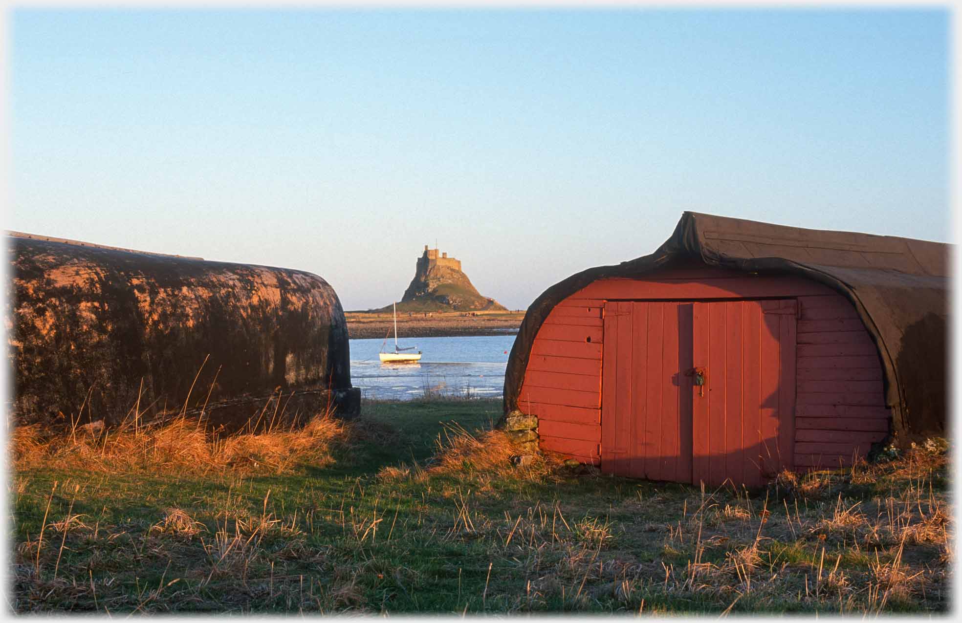 Upturned boats framing castle on rock, one with doors in its end.