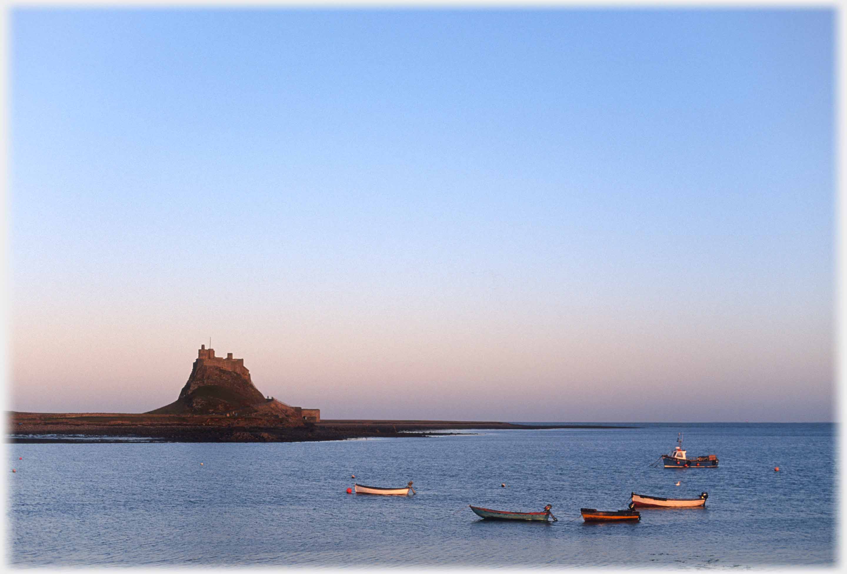 Castle on hillock, sea in foreground with five boats anchored.