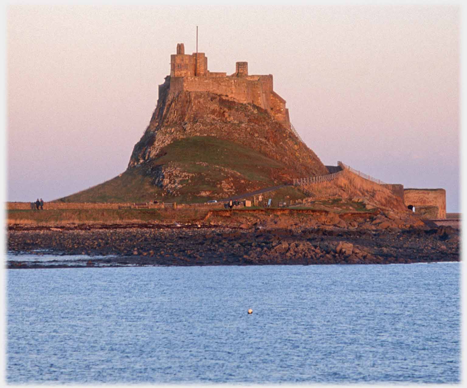 Closer shot of castle on hillock, two people just visible.