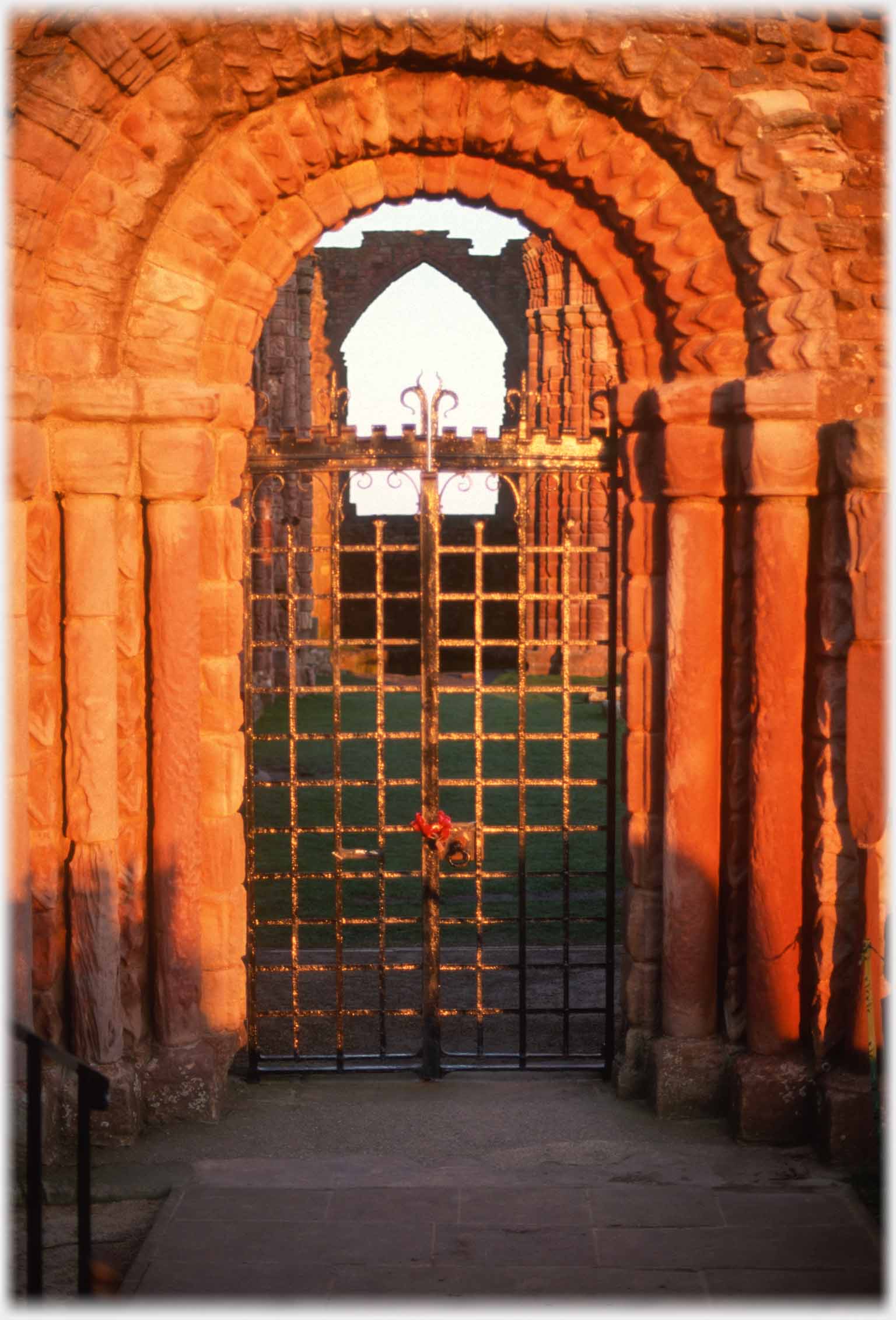 Metal work gate in stone arch with chevron carving.