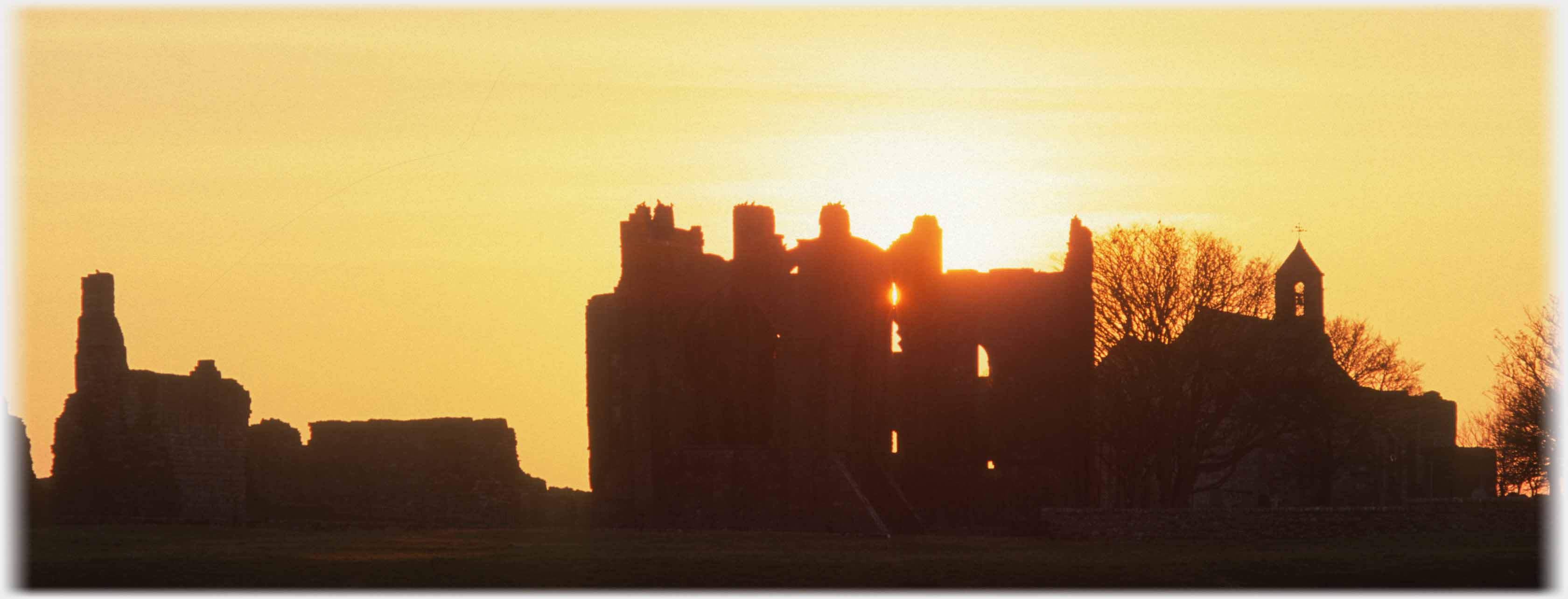 Silhouette of ruined building with strong sun behind.