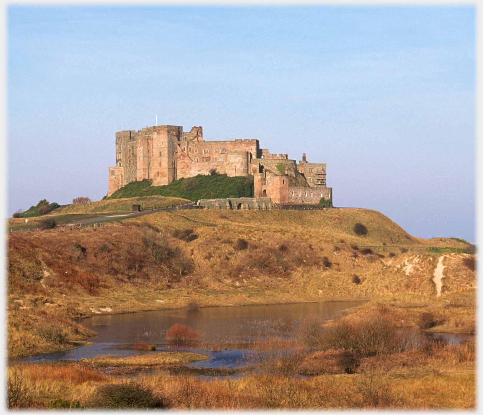 Castle on apparent mound with pool in foreground.