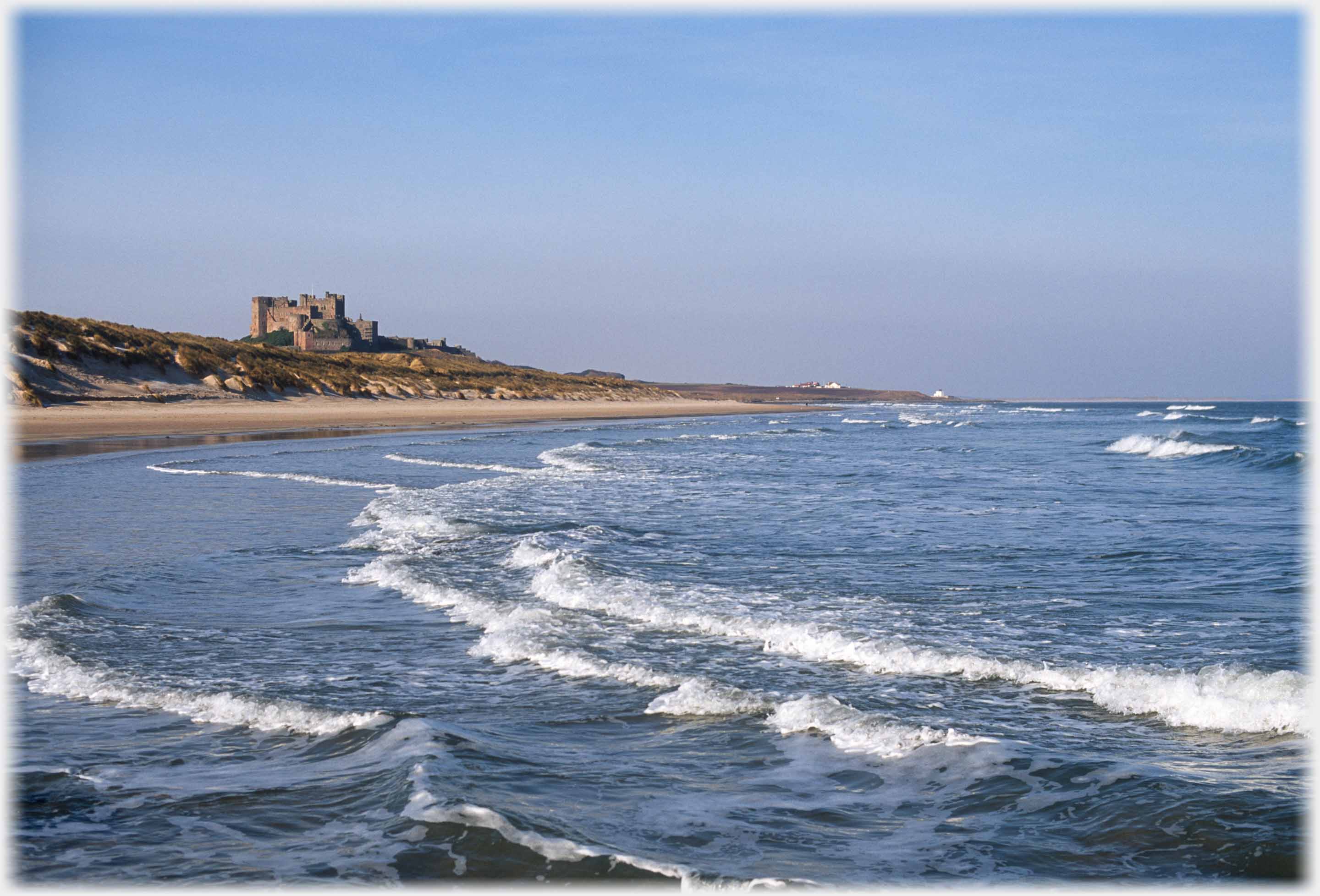 Waves coming into bay with castle at far side.