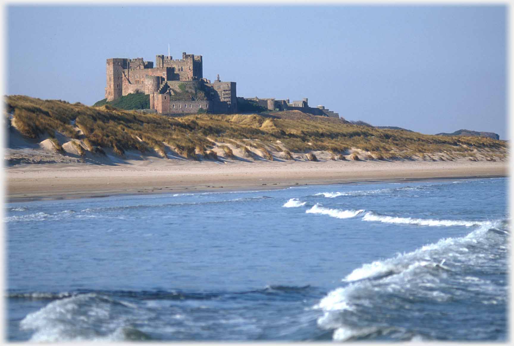 Sea, shore line and castle behind.