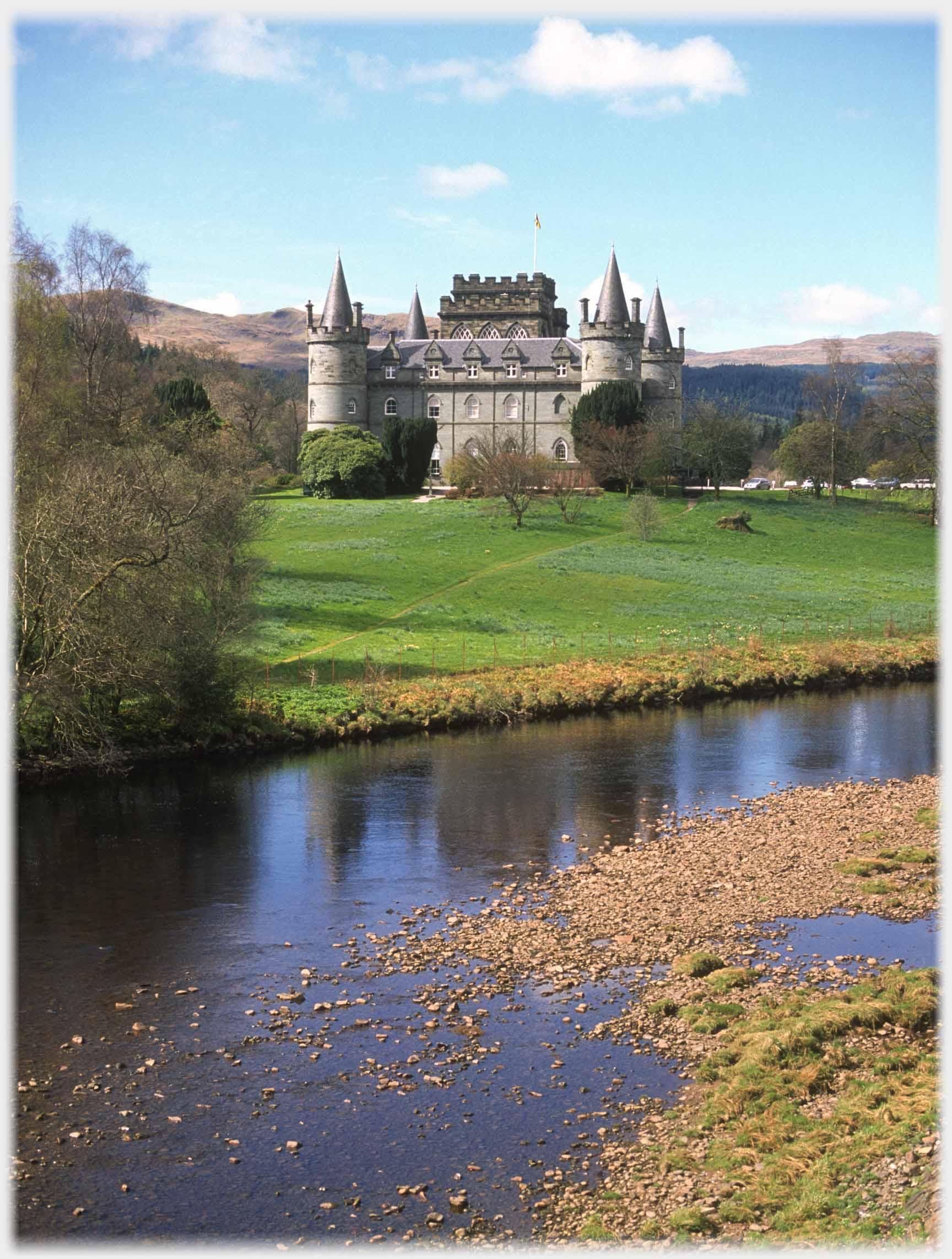 Gothic towered castle beyond river.