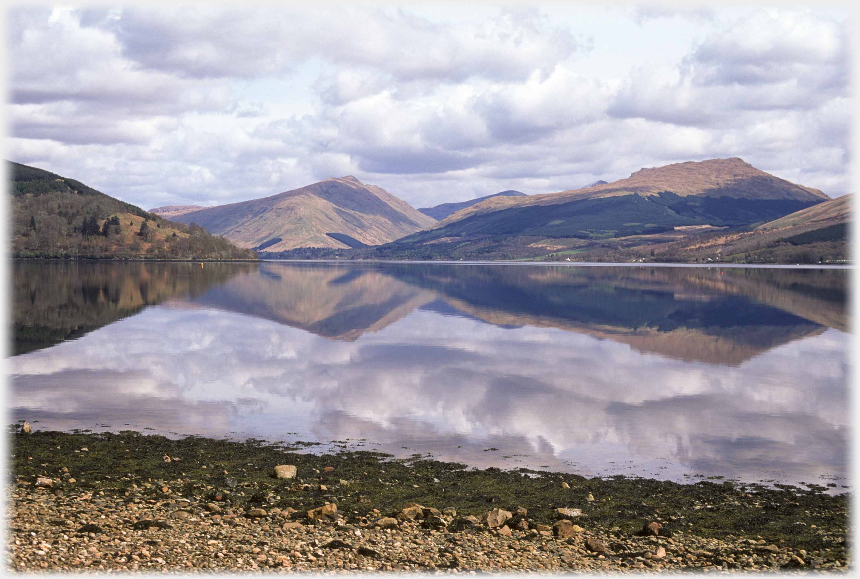 Hills reflected in flat calm water.