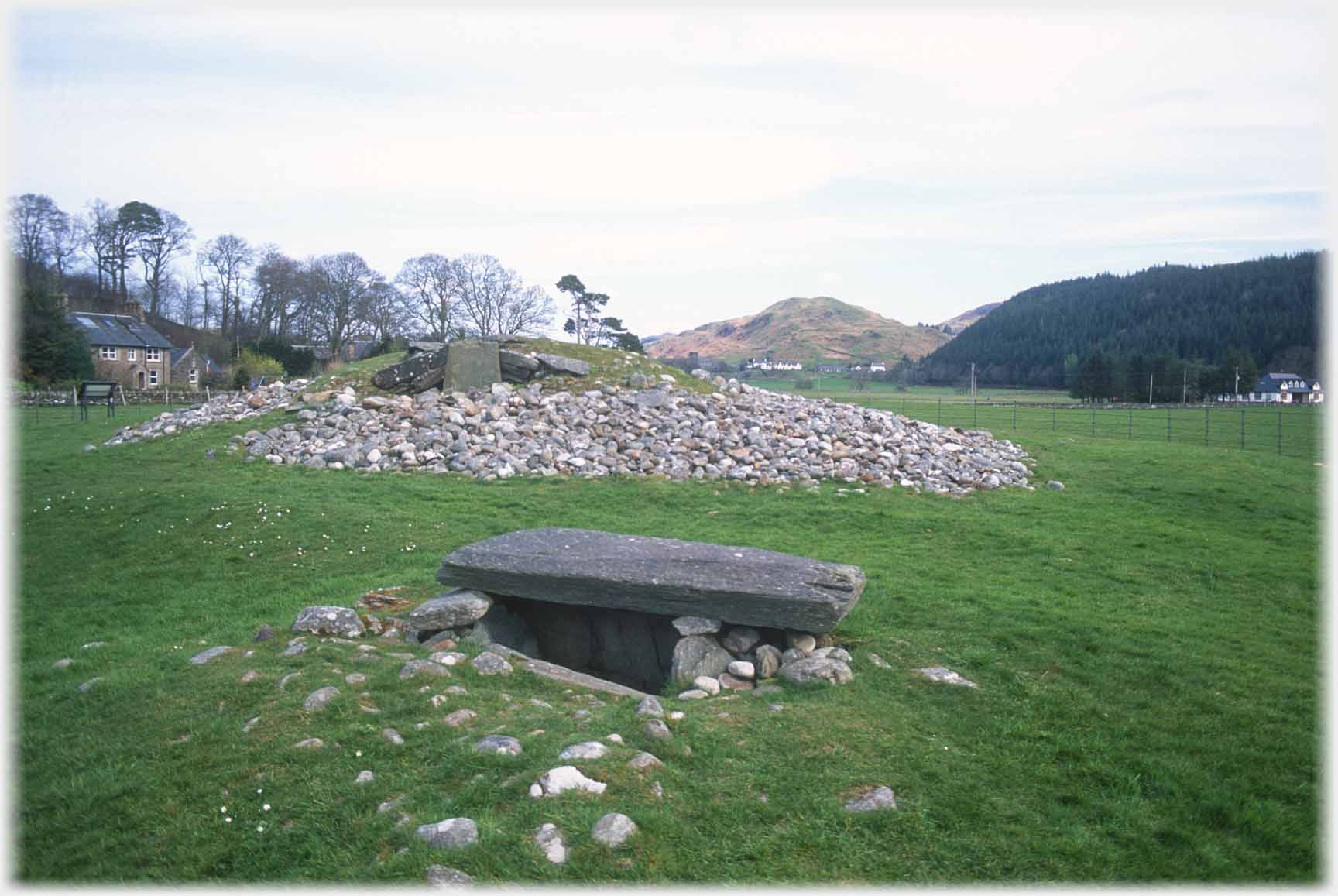 Mound of stones with grave in front.