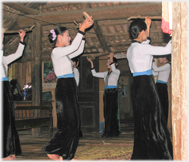 Women circling holding mock instraments over their heads.