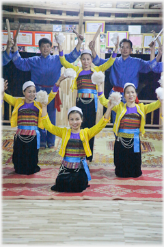 Two men and a woman standing behind three women kneeling all holding pompoms.