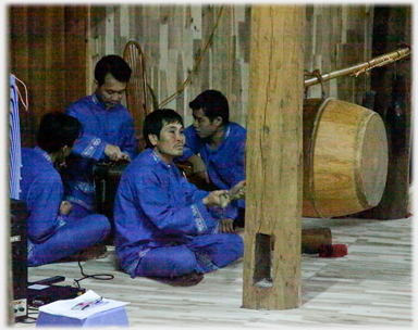 Four men in a corner, one drumming.