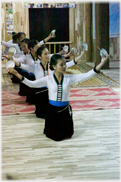 Line of women kneeling holding bowls and chopsticks.