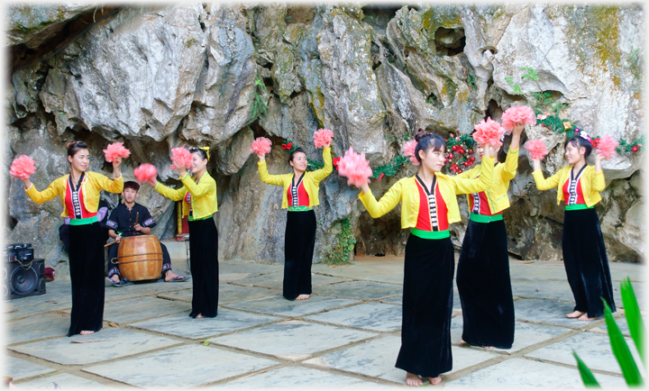 Outside against rocks six women standing shaking pompoms.