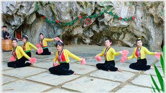 Six women with pompoms kneeling.