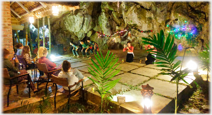 'Stage' area with dancers, audience to left, and rocks behind.