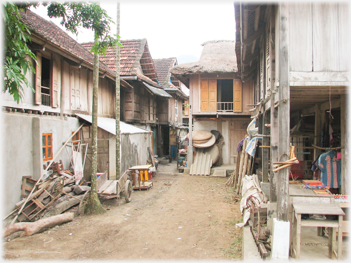 A narrowing lane with piles of building and household materials.
