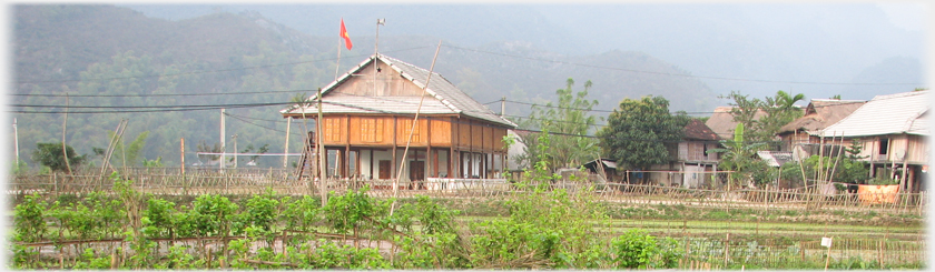 The completed community centre standing in the fields with village houses to one side.