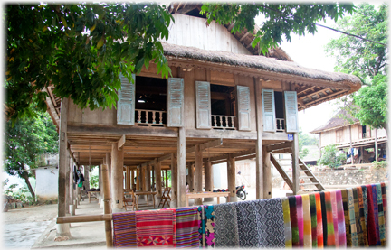 Large Thai house with line of coloured cloths for sale.