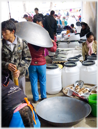 Woman under large wok.